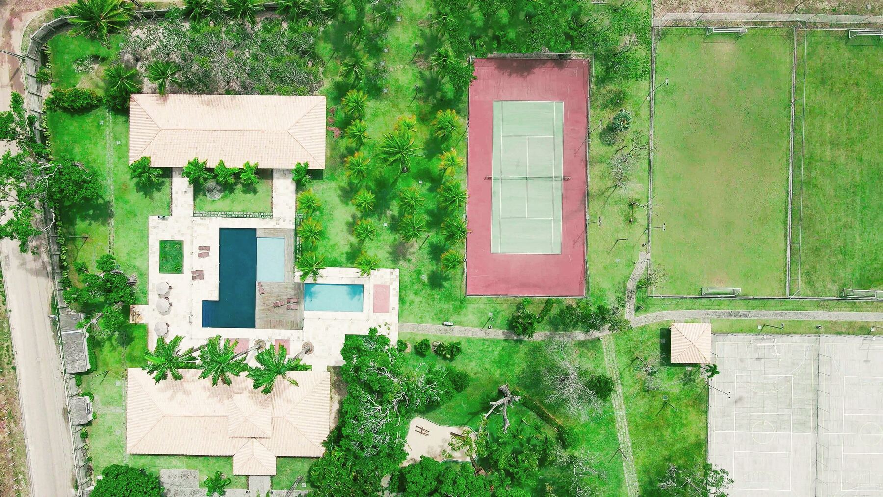 Vista superior do Home Club com quadra de tênis e piscinas