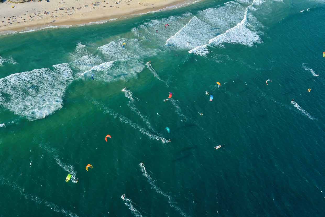 Vista aérea do mar com praticantes de kitesurf