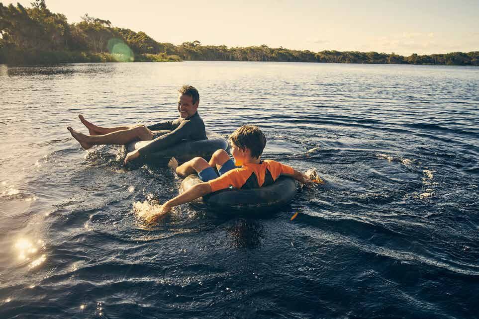 Pai e filho em boias na lagoa ao entardecer